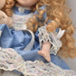 Vintage Porcelain Doll With Teddy Bear Blonde Hair, Blue Eyes and Blue Silk Dres